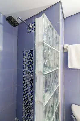 a blue bathroom with a shower with a glass door at Apartamento cerca al Mar in Cartagena de Indias