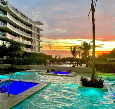 a resort swimming pool with a sunset in the background at Espectacular frente al Mar- Morros Zoe - Playa Manzanillo Cartagena in Cartagena de Indias