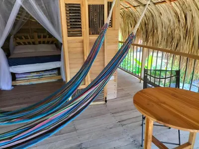 a hammock in a room with a bed and a table at Bungalow Palmar del Viento by AMAUNA in Moñitos