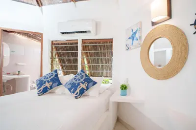 a bedroom with a bed with blue and white pillows at Isla Mulata, Islas del Rosario in Isla Grande