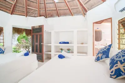two beds in a room with white walls and blue pillows at Isla Mulata, Islas del Rosario in Isla Grande