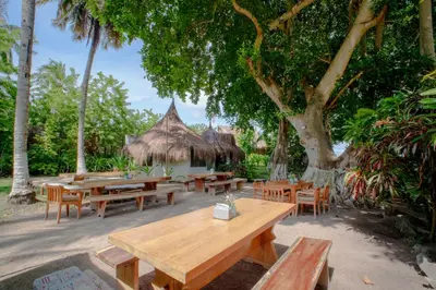 a group of tables and chairs under a tree at Isla Mulata, Islas del Rosario in Isla Grande