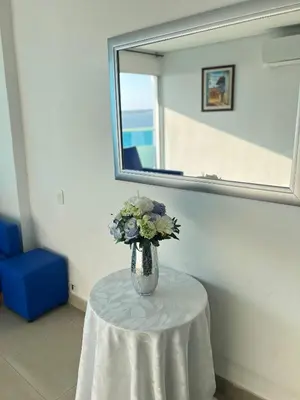 a vase of flowers sitting on a table under a mirror at Apartamento torres del lago in Cartagena de Indias