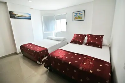 two beds in a small room with red pillows at Apartamento torres del lago in Cartagena de Indias