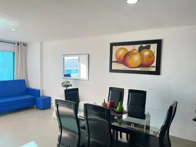 a dining room with a table with chairs and a painting of apples at Apartamento torres del lago in Cartagena de Indias