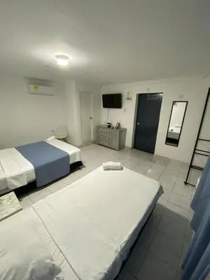a hotel room with two beds and a television at Habitación cerca al aeropuerto 1 in Cartagena de Indias