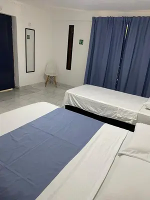 two beds in a room with blue curtains at Habitación cerca al aeropuerto 1 in Cartagena de Indias