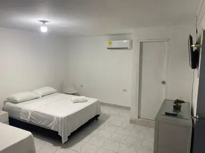 a white room with a bed and a television at Habitación cerca al aeropuerto 1 in Cartagena de Indias