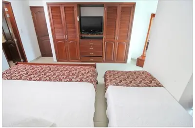 two beds in a room with a tv and a cabinet at torres del lago apartamento in Cartagena de Indias