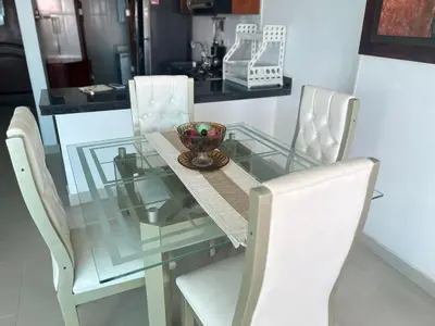 a glass table with white chairs and a bowl on it at torres del lago apartamento in Cartagena de Indias