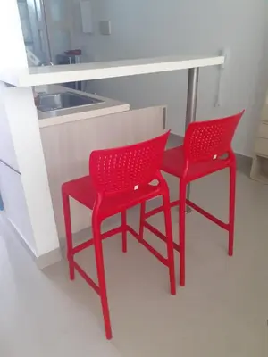 two red chairs sitting next to a table in a kitchen at Hermoso apartamento con piscina frente al mar - Primera Ensenada in Coveñas