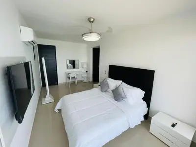 a bedroom with a large white bed and a desk at Front beach apartment close to the Cartagena letters in Cartagena de Indias