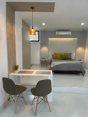 a bedroom with a bed and two chairs and a desk at Apartasuites Mardini in Cartagena de Indias
