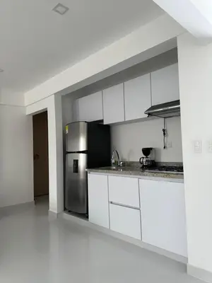 a kitchen with white cabinets and a stainless steel refrigerator at Apartasuites Mardini in Cartagena de Indias