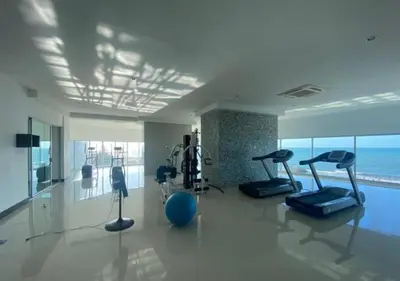 a gym with cardio equipment in a large room with the ocean at Apartamento frente al mar con vista única en Cartagena in Cartagena de Indias