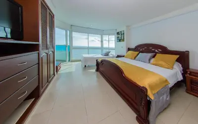 a bedroom with a large bed with a television and the ocean at Torres del lago de 2 habitaciones, 1201 in Cartagena de Indias