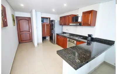 a kitchen with wooden cabinets and a black counter top at Torres del lago de 2 habitaciones, 1201 in Cartagena de Indias