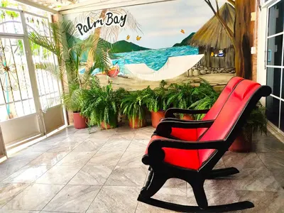a red chair sitting in front of a room with a boat at SGH Hotel Palm Bay Bello Horizonte in Santa Marta