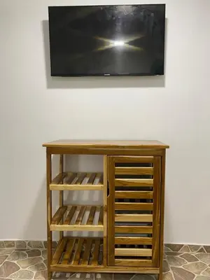 a tv hanging on a wall with a wooden cabinet at Ecohotel La Reserva in Piojó