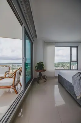 a bedroom with a bed and a table and windows at SkyMar Luxury 27 in Cartagena de Indias