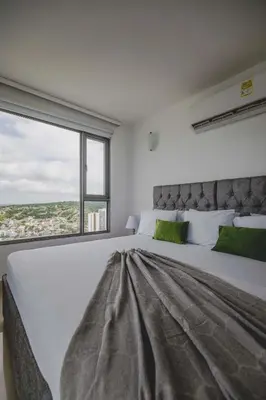 a bedroom with a large white bed with a large window at SkyMar Luxury 27 in Cartagena de Indias