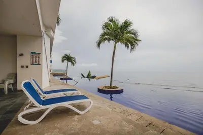 a chair and a palm tree on the beach at Frente al Mar home office 7B in Cartagena de Indias