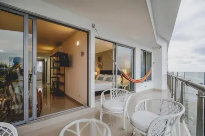 a balcony with white chairs and a bedroom at Frente al Mar home office 7B in Cartagena de Indias