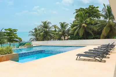 a swimming pool with lounge chairs and the ocean at Magico Apartamento Frente al Mar 3 Habitaciones TR21 in Coveñas