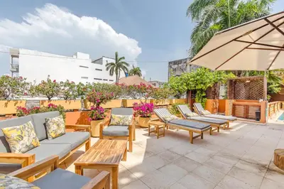 a patio with chairs and tables and an umbrella at 2CM-J1 APARTAMENTO DE 2 ALCOBAS CON VISTA Y PISCINA EN GETSEMANI in Cartagena de Indias