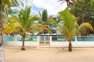 two palm trees on a beach in front of a building at Hermoso Apartamento Frente al Mar 2 Habitaciones C13B in Coveñitas