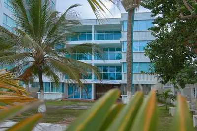 a tall building with palm trees in front of it at Hermoso Apartamento Frente al Mar 2 Habitaciones C13B in Coveñitas