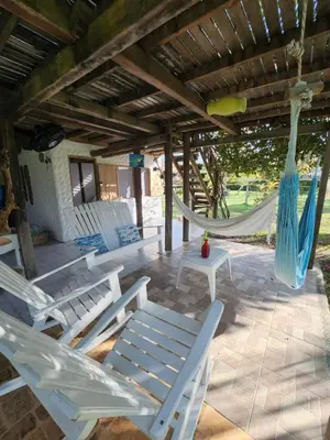 a patio with white chairs and a hammock at Cabana Ferrer in Notecebes