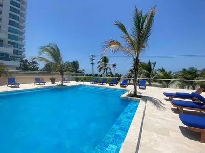 a swimming pool with blue chairs and palm trees at Comodo Apartamento en morros epic! in Cartagena de Indias
