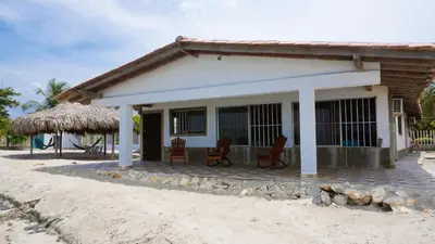 a small house with a thatched roof on a beach at Cabaña Aire Viento Sol in Puerto Viejo