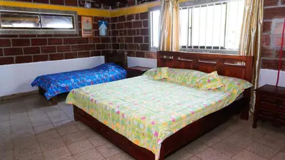 a bedroom with two beds and a brick wall at Cabaña Aire Viento Sol in Puerto Viejo