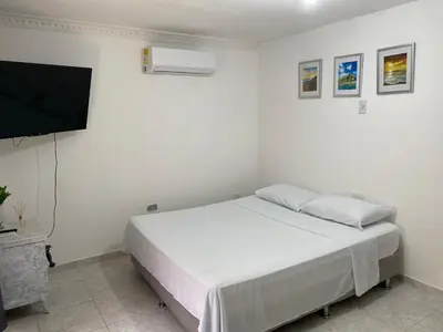 a white bedroom with a bed and a flat screen tv at Habitación cerca al aeropuerto 2 in Cartagena de Indias