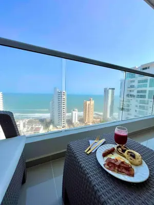 a table with a plate of food and a glass of wine at Apartamento Moderno y lujoso con vista al mar Piso 1903 - cerca a ciudad amurallada in Cartagena de Indias