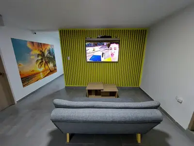 a room with a couch and a tv on a wall at Tranquilo Apartamento Central Cerca a la Playa Puerto Colombia in Puerto Colombia