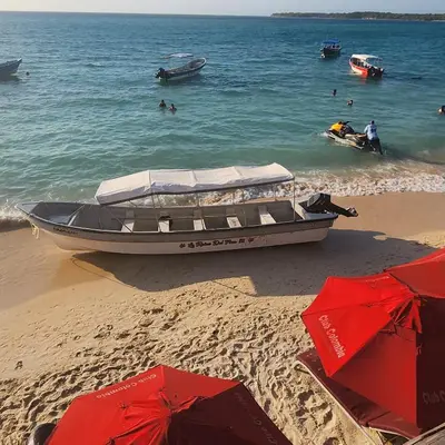 a boat on a beach with people in the water at Ecohotelhector in Playa Blanca