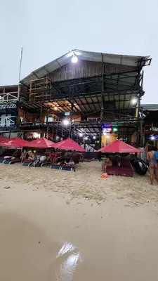 a building with red umbrellas and people on the beach at Ecohotelhector in Playa Blanca