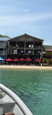 a building with tables and red umbrellas on a beach at Ecohotelhector in Playa Blanca