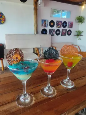 three cocktails sitting on top of a wooden table at Freedom Beach Club in Baru