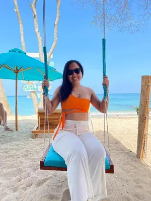 a woman sitting on a swing on the beach at Freedom Beach Club in Baru