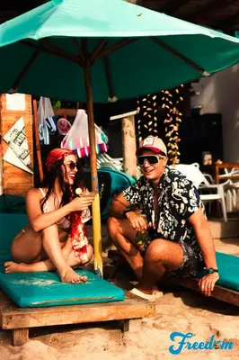 two people sitting on the beach under an umbrella at Freedom Beach Club in Baru