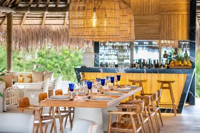 a dining room with a table and chairs and a bar at Hotel Agua Baru by Mustique in Baru