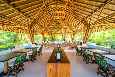 a restaurant with tables and chairs and a wooden ceiling at Hotel Agua Baru by Mustique in Baru