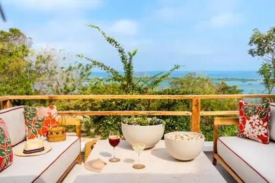 a table with two glasses of wine on a balcony at Hotel Agua Baru by Mustique in Baru