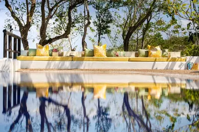 a table with yellow and white pillows next to a body of water at Hotel Agua Baru by Mustique in Baru