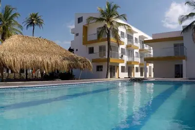 a swimming pool in front of a building with palm trees at Apto 1er piso frente a la playa y con piscina in San Bernardo del Viento