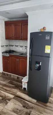 a kitchen with a black refrigerator and wooden cabinets at Cartagena apto estudio piso 12 frente a la playa in Cartagena de Indias